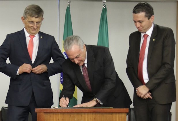 Presidente Michel Temer (centro) assina o projeto de lei de autoria do deputado federal Fausto Pinato (direita), acompanhado pelo deputado federal Darcísio Perondi (esquerda)