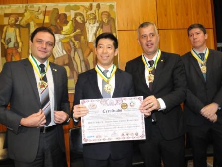 O presidente do Ibrachina, Thomas Law, recebe a homenagem das mãos do deputado federal Evair Vieira de Melo (à esquerda de Law)