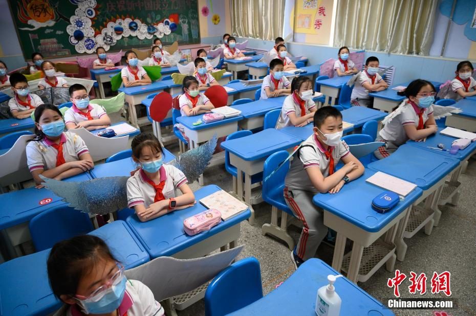 Alunos de uma escola chinesa usam uma “asa de um metro” nas costas, feita de material reciclado, para manter o distanciamento social